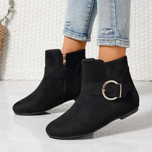 Close-up view of black suede ankle boots with side zipper and decorative gold buckle