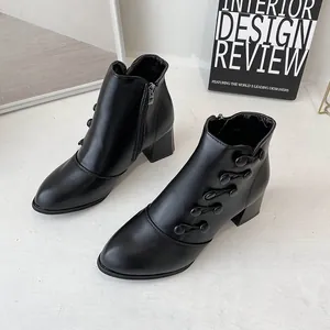 Detailed view of black pointed-toe ankle boots with decorative toggle button design