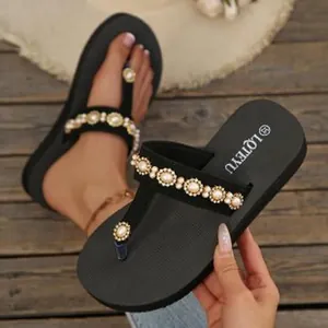 Close-up view of elegant black platform flip flops with pearl and rhinestone strap details.