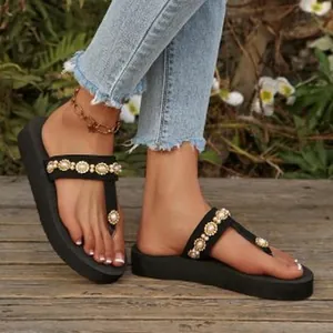 Close-up view of black platform flip-flops decorated with pearls and sparkly rhinestones