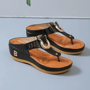 Detalle de sandalias de cuña negras para mujer con decoración de logo B dorado