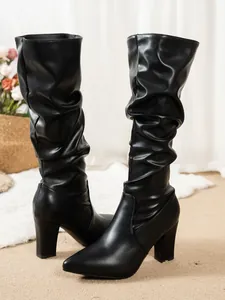 Elegant black slouchy knee-high boots featuring a chunky high heel and pointed toe design
