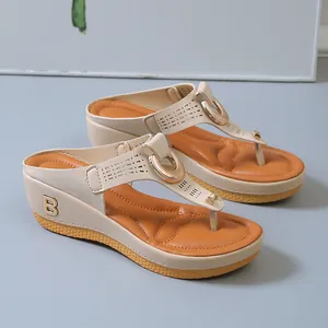 Vista detallada de las chanclas beige con cuña para mujer y emblema B dorado