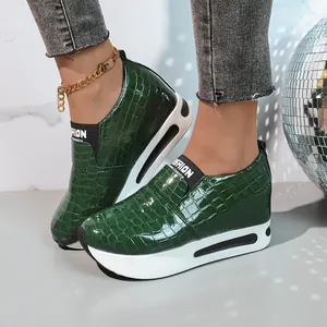 Dettaglio della trama coccodrillo verde su sneakers con zeppa e plateau.