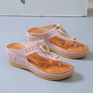 Vista detallada de chanclas de cuña rosas con emblema B dorado y plantilla suave