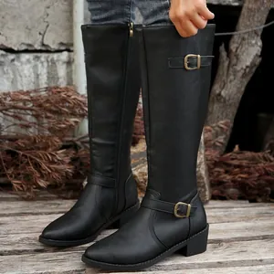 Close-up of black knee-high knight boots with decorative metal buckles and low heels.