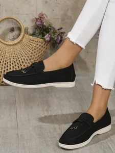 Detailed view of black loafers with white soles worn with white distressed denim jeans