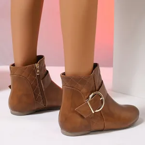 Detail view of brown quilted ankle boots with large gold buckle and side zipper.