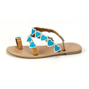 Detailed side view of Bohemian flat sandals featuring blue embroidered heart appliques