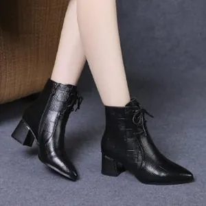 Detail view of black pointed-toe ankle boots with crocodile embossed pattern and block heels.