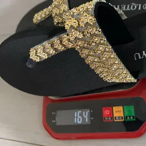 Black platform flip-flops with gold rhinestones being weighed on a scale at 164g