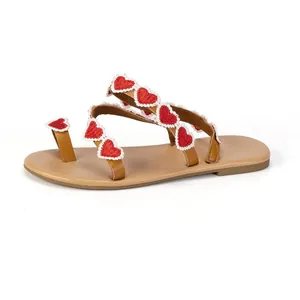 Detailed side view of bohemian flat sandals with red heart embroidery and white lace borders