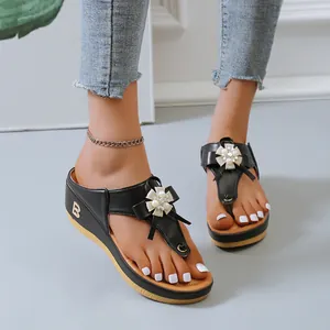 Primer plano de sandalias de cuña negras con un adorno decorativo de flores de perlas