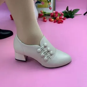 Elegant beige mid-heel pumps featuring unique button details and a sleek pointed toe design