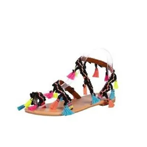Close-up view of bohemian flat sandals featuring vibrant colorful tassels and woven straps