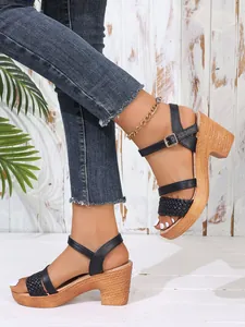 Side view of black strappy sandals with woven chunky heels and gold buckle closure.