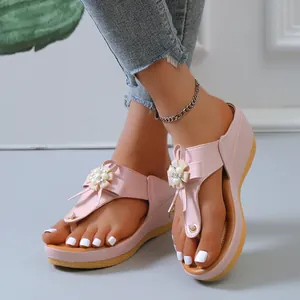 Primer plano de elegantes sandalias de cuña rosas con decoraciones de flores y perlas