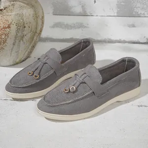 Detail shot of stylish grey slip-on loafers featuring decorative tassels and gold rings