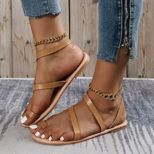 Close-up view of bohemian tan flat Roman sandals featuring cross straps and toe loop design