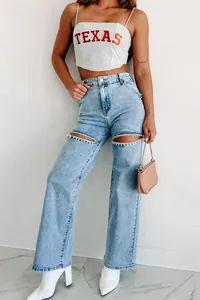 Détail d'un jean droit avec des découpes ornées d'une chaîne en strass sur les jambes