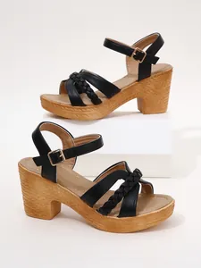Close-up detail showing the black braided straps and straw-textured chunky heel of the sandals