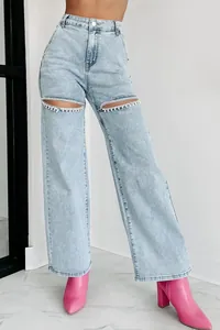 Vue détaillée du jean taille haute avec des chaînes en strass aux genoux déchirés.