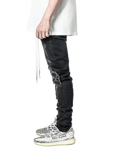 Side view detail of men's distressed black skinny motorcycle jeans with knee rips.