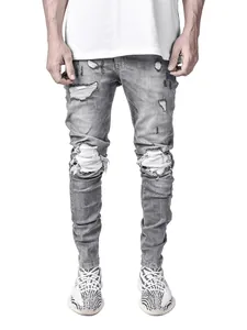 Close-up of mens grey skinny jeans featuring distressed ripped knee details and wash