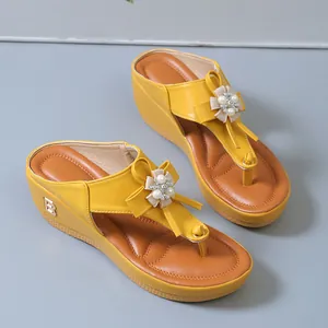 Detalle de sandalias de cuña amarillas con elegantes adornos de flores de perlas