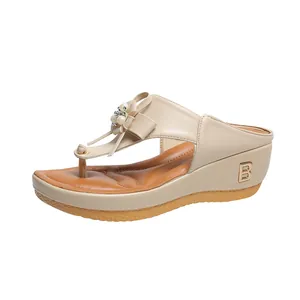 Detalle de elegantes sandalias de cuña beige con adornos de perlas y flores decorativas
