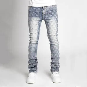 Detail view of men's stacked denim jeans with pearl embellishments and acid wash finish.