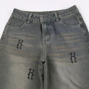 Dettaglio di jeans in denim vintage invecchiato con stampe con motivo H gotico