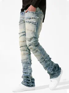 Close-up of men's stacked denim jeans with patchwork frayed details in light blue wash.