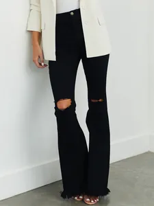 Detailansicht einer schwarzen Schlagjeans für Damen mit Rissen und trendigem Fransensaum.