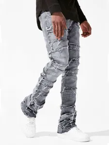 Detail of grey distressed patchwork denim pants with frayed edges and stacked bottom.