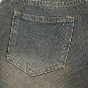 Dettaglio macro di una tasca in denim lavato vintage con cuciture a contrasto di qualità