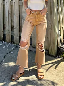 Women's tan high-waisted ripped straight-leg jeans with frayed hem in casual outdoor setting