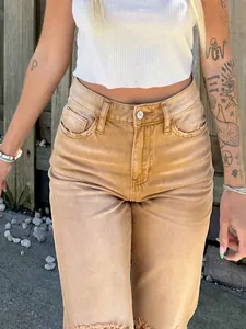 Detail of tan high-waisted distressed straight jeans with frayed pockets