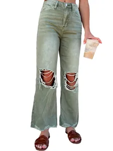Detailed view of women's olive green distressed straight-leg baggy jeans with ripped knees