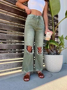 Close-up of women's green ripped straight-leg jeans shown in a lifestyle setting