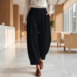 Elegant black high-waisted loose harem trousers shown in a modern professional office setting