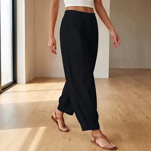 Model wearing high-waist black wide-leg harem pants in a bright minimalist sunlit room