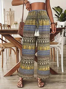 Dettaglio di pantaloni bohémien a vita alta con elastico in vita e nappe