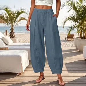 Detailed view of women's loose solid blue cropped harem pants in a beach setting