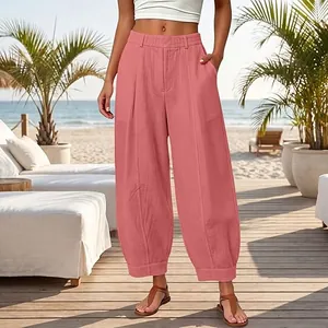 Detail showing the pleated waist and pockets of these pink loose harem pants in a beach setting
