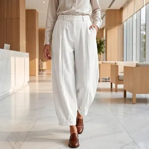 Close-up detail of white loose-fit harem pants featuring pleated waist and cuffed hem