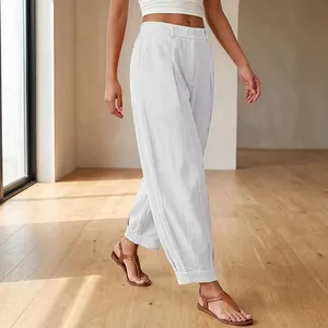 Detailed side view of white loose-fit cropped harem pants worn by a model in an interior