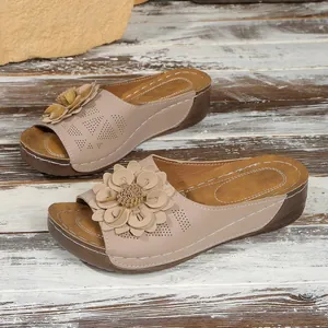 Élégantes mules beiges à talons compensés avec une décoration florale détaillée.