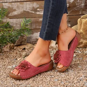 Close-up of stylish burgundy wedge sandals with flower detail and white stitching