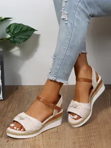 Vista dettagliata di eleganti sandali espadrillas con zeppa, fiocco e cinturino alla caviglia.